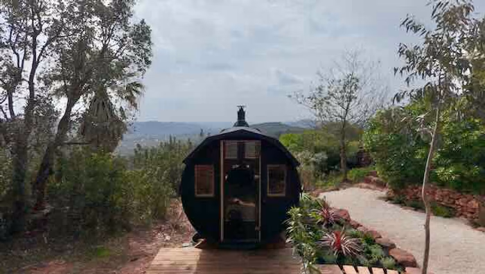 The barrel sauna at Rose Mountain on its wooden deck, valley view behind